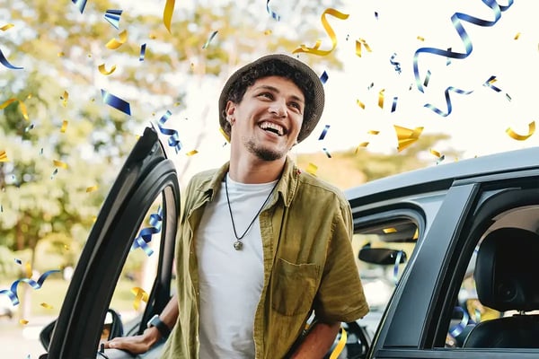 Man celebrating with confetti as he opens his car door.